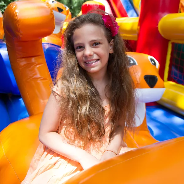 Cute little girl plays in bouncing castle — Stock Photo, Image