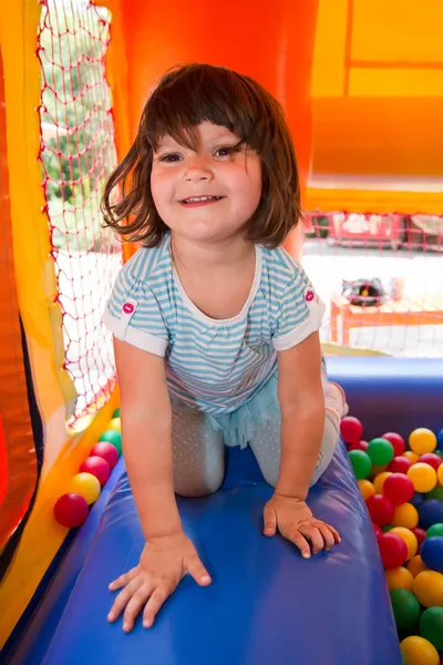 Menina que joga no castelo de salto inflável — Fotografia de Stock