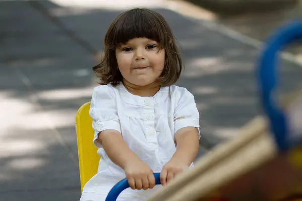 Mignonne petite fille sur swing dans la cour de récréation — Photo