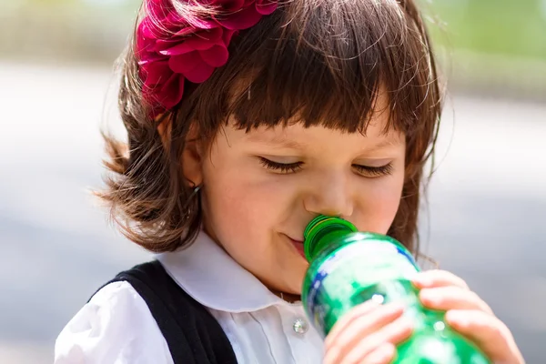 Liten flicka vatten från flaska — Stockfoto