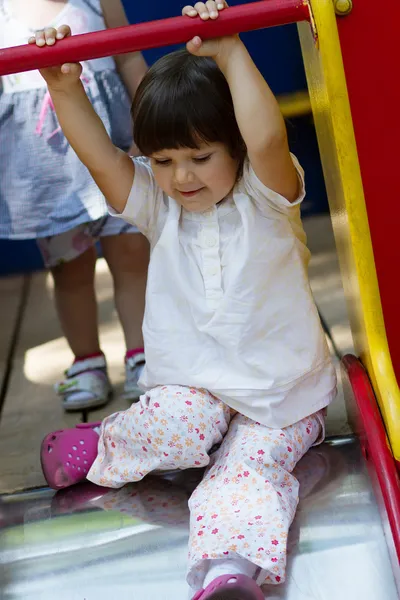 Niña deslizándose en el patio de recreo — Foto de Stock