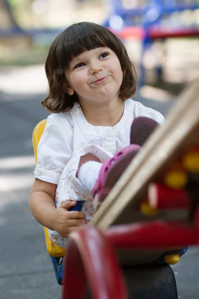 สาวน้อยน่ารักบนสวิงในสนามเด็กเล่น — ภาพถ่ายสต็อก