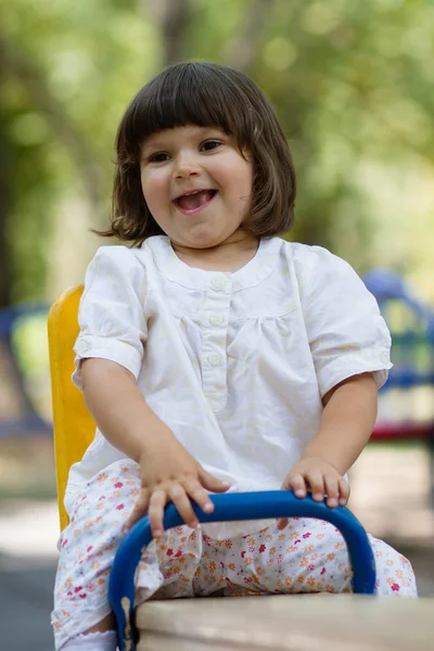 Mignonne petite fille sur swing dans la cour de récréation — Photo