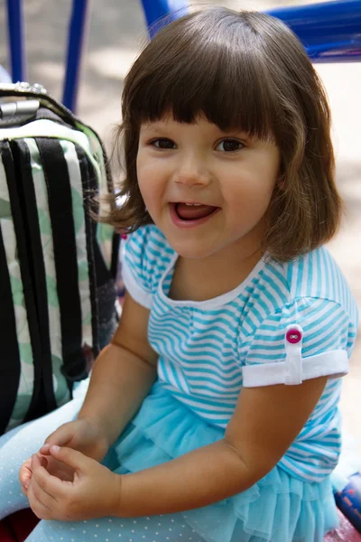 Pequeña chica divertida sonriendo en un banco —  Fotos de Stock