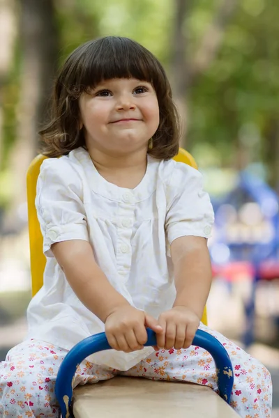 Cute little girl on swing in the playground — Stock Photo, Image