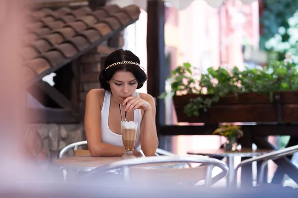 Junges Mädchen trinkt Cappuccino in einem Café — Stockfoto