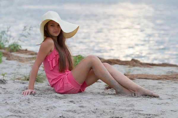 可爱的年轻女孩在帽子坐在沙滩上 — 图库照片
