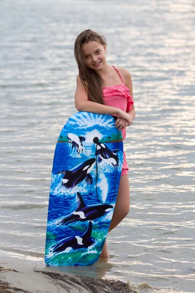 Chica joven con tabla de surf sonriendo —  Fotos de Stock