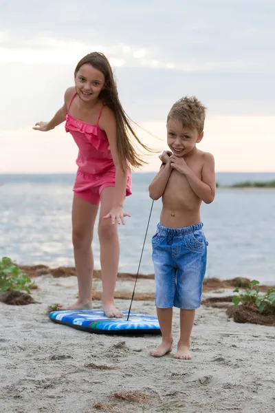 Niños jugando con tabla de surf en la playa —  Fotos de Stock