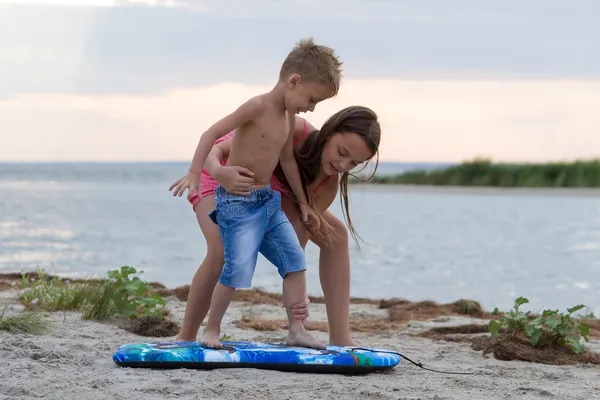 Sister teaching her brother how to surf — Stock Photo, Image