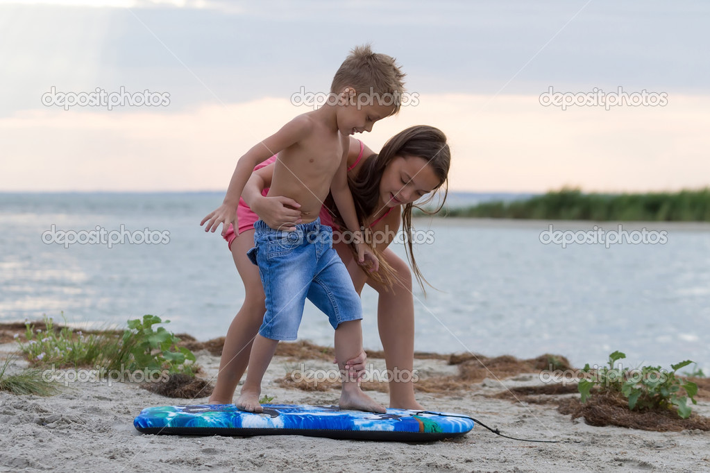 Sister teaching her brother how to surf