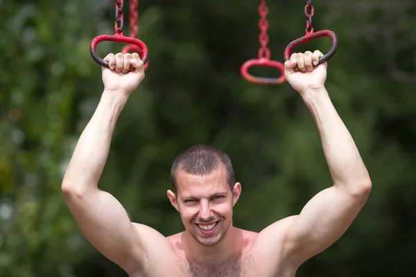 Happy young man tightening on iron rings — Stock Photo, Image