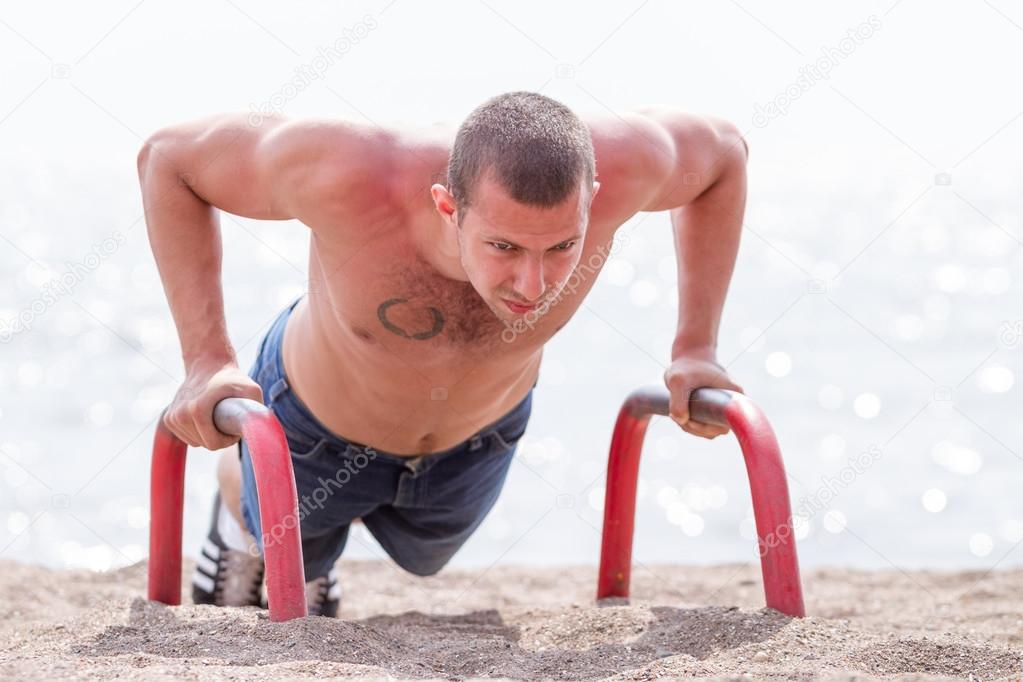 Young man do the push-ups on beach