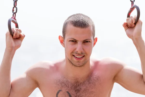 Happy young man exericising on rings — Stock Photo, Image