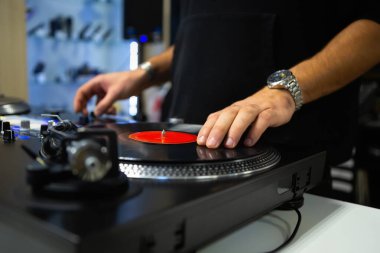 DJ turntable 'a plak çiziyor. Disk jokeyi, müzik mağazasında masaları ve ses karıştırıcıyla plakları çizer