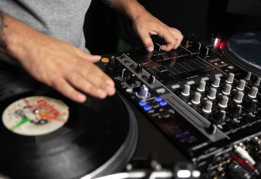 Hip hop DJ 'i pikaplara vinil plaklar çiziyor. Disk jokeyi konserde müziği retro dönüm tablosu oynatıcısı ve ses karıştırıcı aygıtlarıyla karıştırıyor