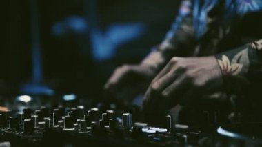 Tekno DJ gece kulübündeki partide müzik çalıyor. Profesyonel konser disk jokeyinin sahnede müzik parçalarını midi ses karıştırıcı ve turntable ile karıştırdığı video klip.
