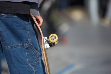 Kaykaycının elinde eski çizikler, açık havada kaykay pisti.