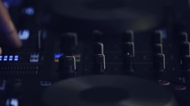 DJ, müziği ses karıştırıcı cihazıyla karıştırıyor. Profesyonel disk jokeyi video klipte müzik parçalarını karıştırıyor