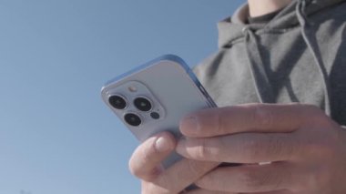 KYIV - 20 Ekim 2021: Güneşli bir günde Iphone 13 Pro cep telefonu cihazına mesaj yazmak. Moda olan Sierra Blue renginde yeni Apple akıllı telefonu gerçek hayatta kullanıldı  