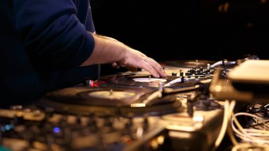Hip hop dj scratching vinyl records on turntables on party in night club. Professional disc jockey scratches analog disc with music clipart