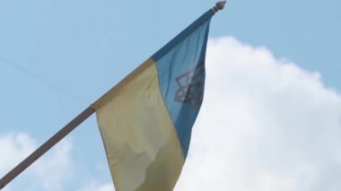 Ukrayna bayrağı direkte. Ukrayna 'nın ulusal bayrağı, dış binaya altın mızrak sembolü monte edilmiş ve ağır çekimde HD video klibiyle çekilmiştir.
