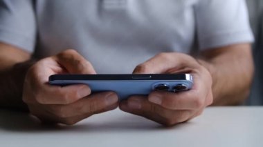 KYIV - 8 Ekim 2021: Moda rengi Sierra Blue ile Iphone 13 Pro telefonunda mobil oyun oynamak. Adam video klipte yeni Apple akıllı telefon aygıtıyla oyun oynuyor  