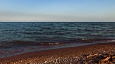 Yaz mevsiminde günbatımı sahili için stok doğa videosu. Dalgalar alacakaranlıkta kumda yuvarlanıyor. 4K 'da çekilen güzel kumlu sahil.