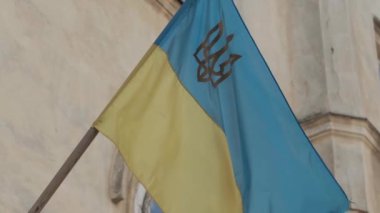 Ukrayna 'nın ulusal bayrağı, dış binanın üzerine direğin üzerinde altın trizub (mızrak) sembolü sallanıyor. Yavaş çekim videosunda.