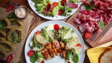 Stok yiyecek görüntüleri. Düzlükte çekilmiş sağlıklı malzemelerle dolu büyük bir akşam yemeği. Taze salata, jambon, mürekkep balığı halkaları Akdeniz restoranında 4k ultra HD video klipte servis ediliyor.