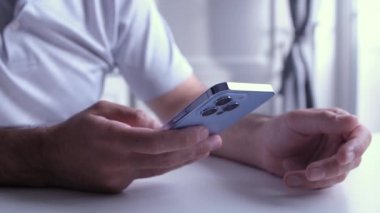 KYIV - 8 Ekim 2021: Moda rengi Sierra Blue ile Iphone 13 Pro telefonunda mobil oyun oynamak. Adam video klipte yeni Apple akıllı telefon aygıtıyla oyun oynuyor  