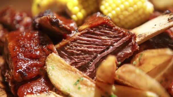 牛の肉はバーベキューグリルで調理され アメリカのレストランで夕食のために焼きポテトとコーンを提供しています — ストック動画