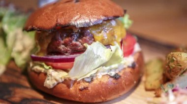 Amerikan bbq restoranında ahşap tabakta servis edilen et pirzolası ve taze sebzeli gurme hamburger.