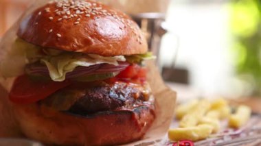 Büyük hamburger ve sığır eti pirzolası susam tohumlu kabuklu çörekler, marul salatası ve ahşap tabakta servis edilen taze sebzelerle servis ediliyor.