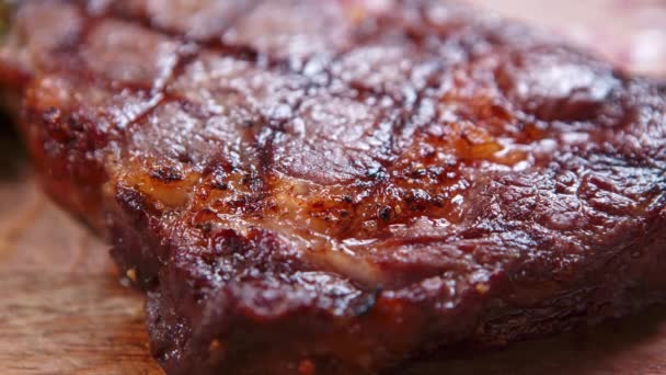 在餐馆的烤架上烤着肉眼牛排 牛肉肉烤成晚餐 放在桌上的木板上 直接从上面拍摄 — 图库视频影像