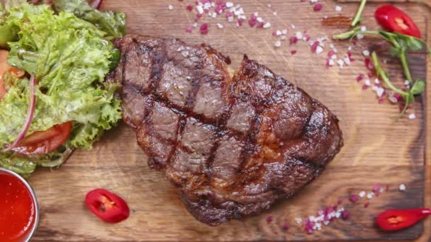 在餐馆的烤架上烤着肉眼牛排 牛肉肉烤成晚餐 放在桌上的木板上 直接从上面拍摄 — 图库视频影像