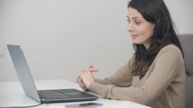 Çevrimiçi sınıf birincisi serbest öğretmen. Dost canlısı esmer kadın bilgisayar başında video görüşmesi yapıyor ve web kamerasıyla konuşuyor.