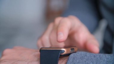 Akıllı saatler ekrana dokunuyor. 4k stok video klipinde çekilen mesajları, internet iletişimini ve teknoloji konseptini okumak için bilek üzerinde modern ukala kullanan adam.