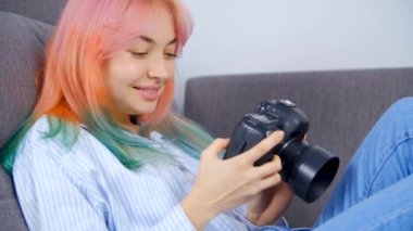 Yaratıcı genç fotoğrafçı kız profesyonel dslr kamerada fotoğraflara bakıyor. Saçları boyalı güzel bir kadın dijital fotoğraf makinesinden büyük bir heyecanla fotoğraf çektikten sonra görüntüleri izliyor. 4k stok video