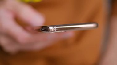 Altın akıllı telefondan internete göz atıyorum. Sosyal medya haberlerine bakmak için modern cep telefonu kullanan bir adam. 4K stok videoda insan cep telefonu taraması. İletişim ve internet teknolojisi kavramı