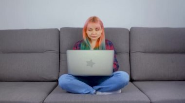 Dizüstü bilgisayarında boyalı saçı olan serbest çalışan kız. Siyah saçlı genç bir kadın, evde kilit altındayken kanepede oturuyor ve defter bilgisayarında çalışıyor. Serbest Lancer 'ın 4K videosu iş başında