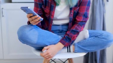 Genç bir kız cep telefonundan haberlere bakıyor. Siyah saçlı, günlük kıyafetler giyen, cep telefonunda sosyal medya uygulaması olan bir genç. 4K içinde telif hakkı olmayan stok videosu.