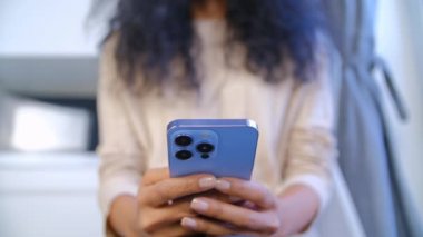 Genç siyahi kadın cep telefonu kullanıyor. İnternet haberlerine göz atıp, akıllı telefonla iletişim kuran biri. Afrikalı kadın modern cep telefonunda uygulamalar kullanıyor. İletişim ve teknoloji kavramı