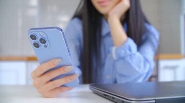 Modern cep telefonu kullanan genç bir kadın. Asyalı kız akıllı telefon cihazında sosyal medya uygulamasını üçlü kamerayla tarıyor. Tecritteyken internet üzerinden iletişim ve alışveriş için kadın kullanımı