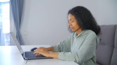 Mutlu bir gülümsemeyle dizüstü bilgisayarda çalışan profesyonel serbest çalışan kadın. Afrikalı kadın tecritte serbest çalışıyor. 4k video içinde dizüstü bilgisayara metin yazan ücretsiz mızrak yazarı