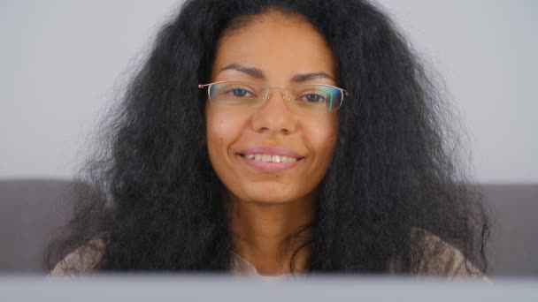 自宅のノートパソコンで働く幸せな若い黒人女性の肖像画 リビングルームのノートパソコンの前で優しい歯の笑顔でポーズをとるプロのフリーランス女性 幸福の概念ビデオ — ストック動画