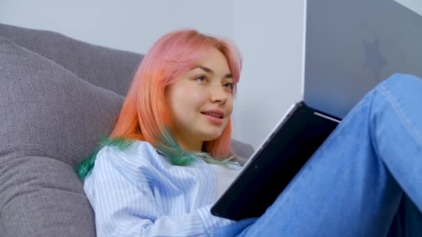 ロックダウン時に自宅のノートパソコンで働く染めの髪を持つフリーランスの女の子のストックビデオ 4K超Hdで撮影されたノートパソコンのキーボードで色の髪のタイピングテキストを持つ若い女性 — ストック動画