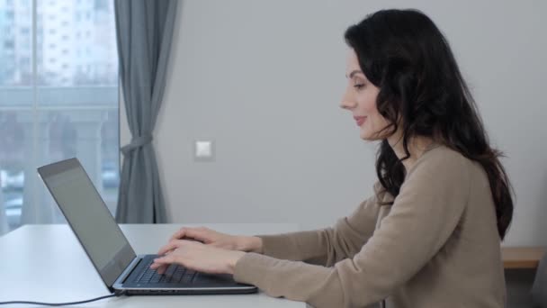 在笔记本电脑上工作的自由职业者女人 熟练的自由长矛作家在家里的笔记本电脑键盘上打字文字 在4K视频中 漂亮的白人女性带着愉快的笑容在关机时做着遥远的工作 — 图库视频影像