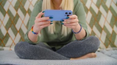 Genç beyaz kadın internetten video izliyor. Beyaz ırk, hızlı internet bağlantısı olan yeni akıllı telefondan canlı yayın yapıyor. Üçlü kameralı modern cep telefonu kullanan kişi.