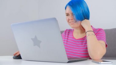 İnternette çalışan mutlu beyaz kadın. Boyalı mavi saçlı hoş bir kadın internet bağlantısıyla uzaktan öğreniyor. Kilit altında serbest çalışan gülümseyen genç kişi